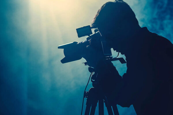Male videographer, cameraman filming a report on the street